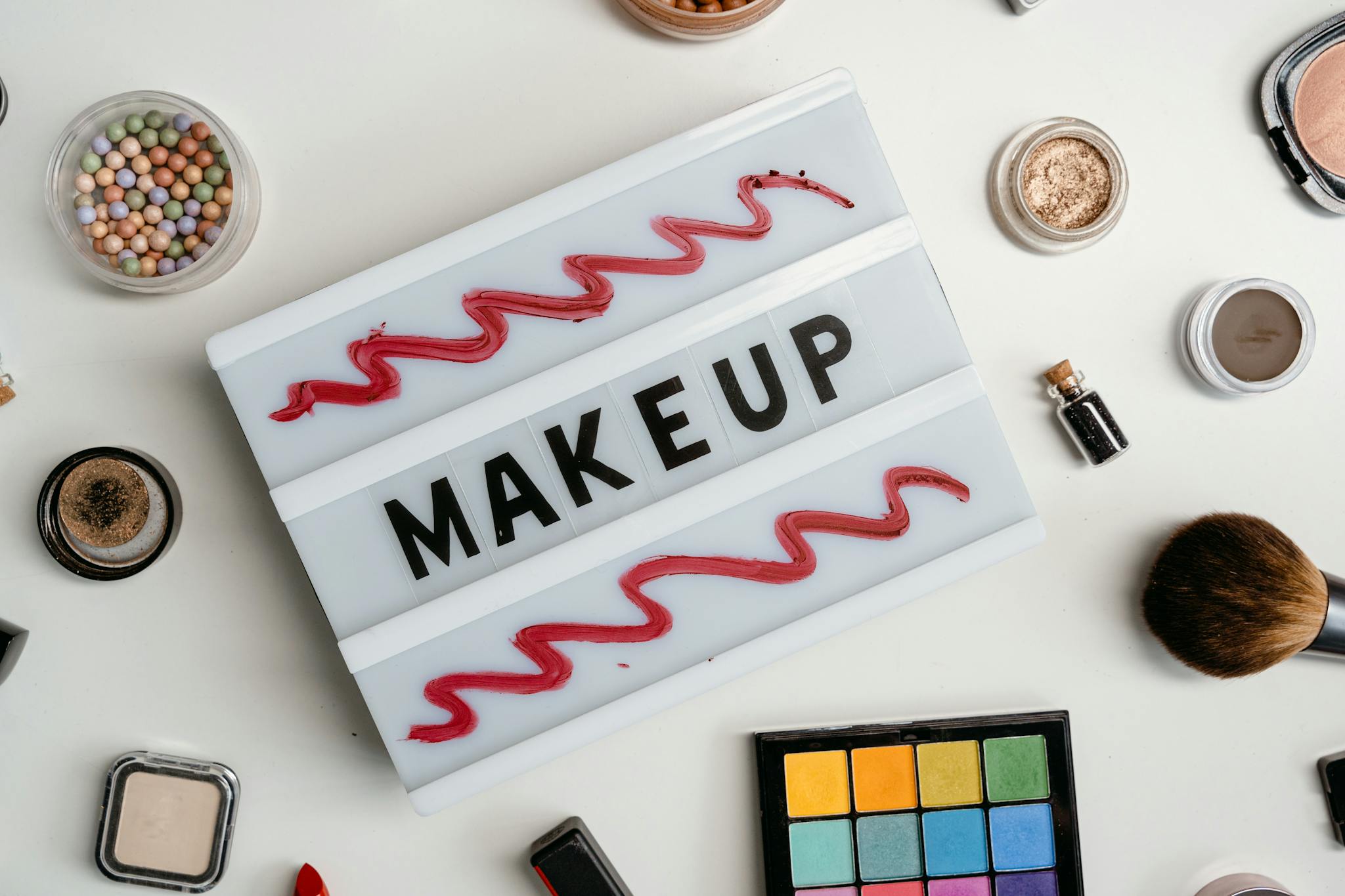 Flat lay of a colorful makeup palette with various beauty products, emphasizing vibrant cosmetics.