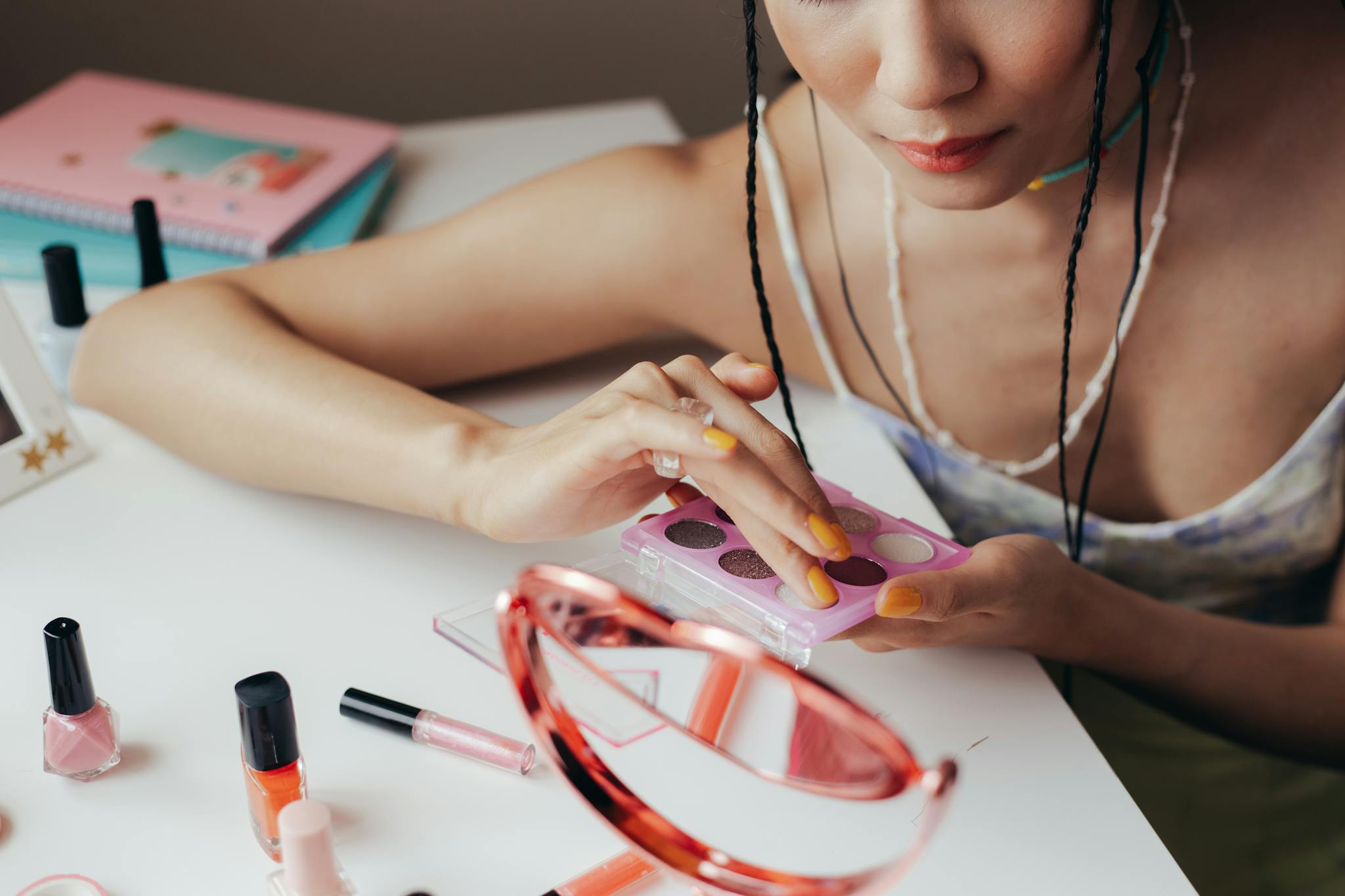 Woman Using Eyeshadow Palette With Cosmetics Scattered